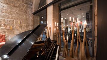 Un piano de cola en una habitación con paredes de piedra y ventanas amplias.