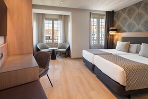 Una habitación de hotel con cama, escritorio, silla y una mesita.