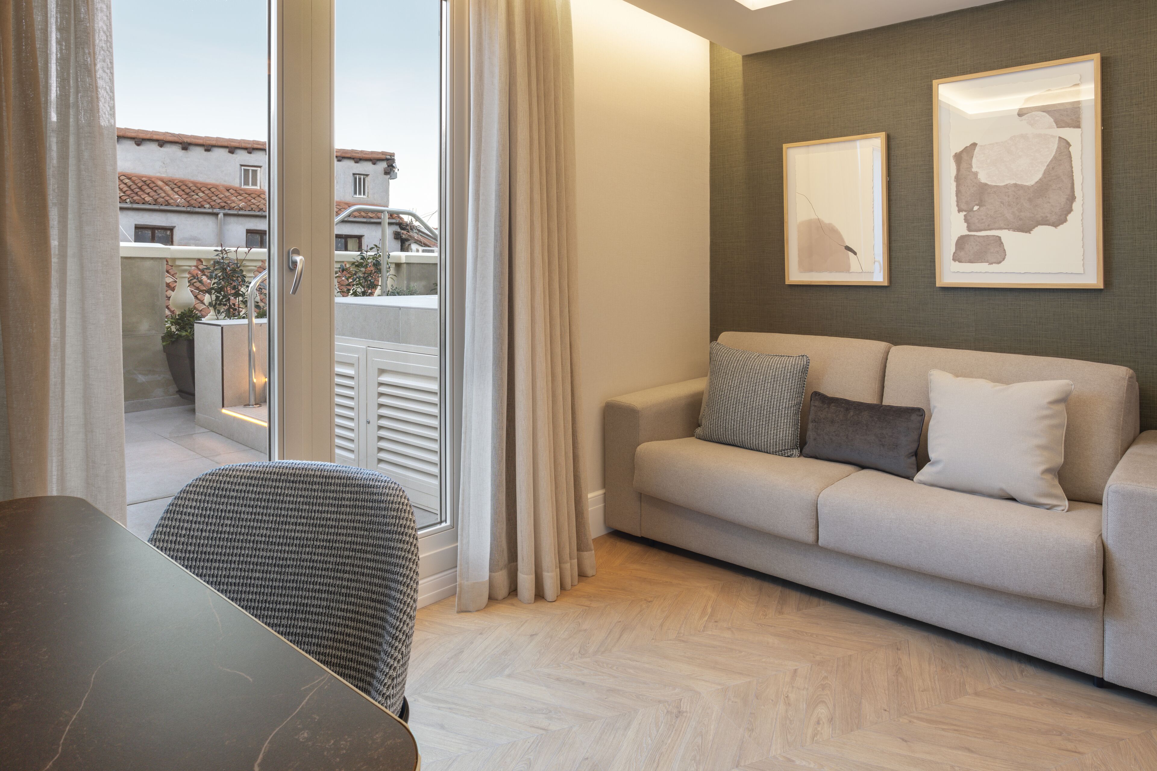 Una sala de estar moderna con un sofá, una mesa de comedor y vistas al exterior a través de un ventanal.