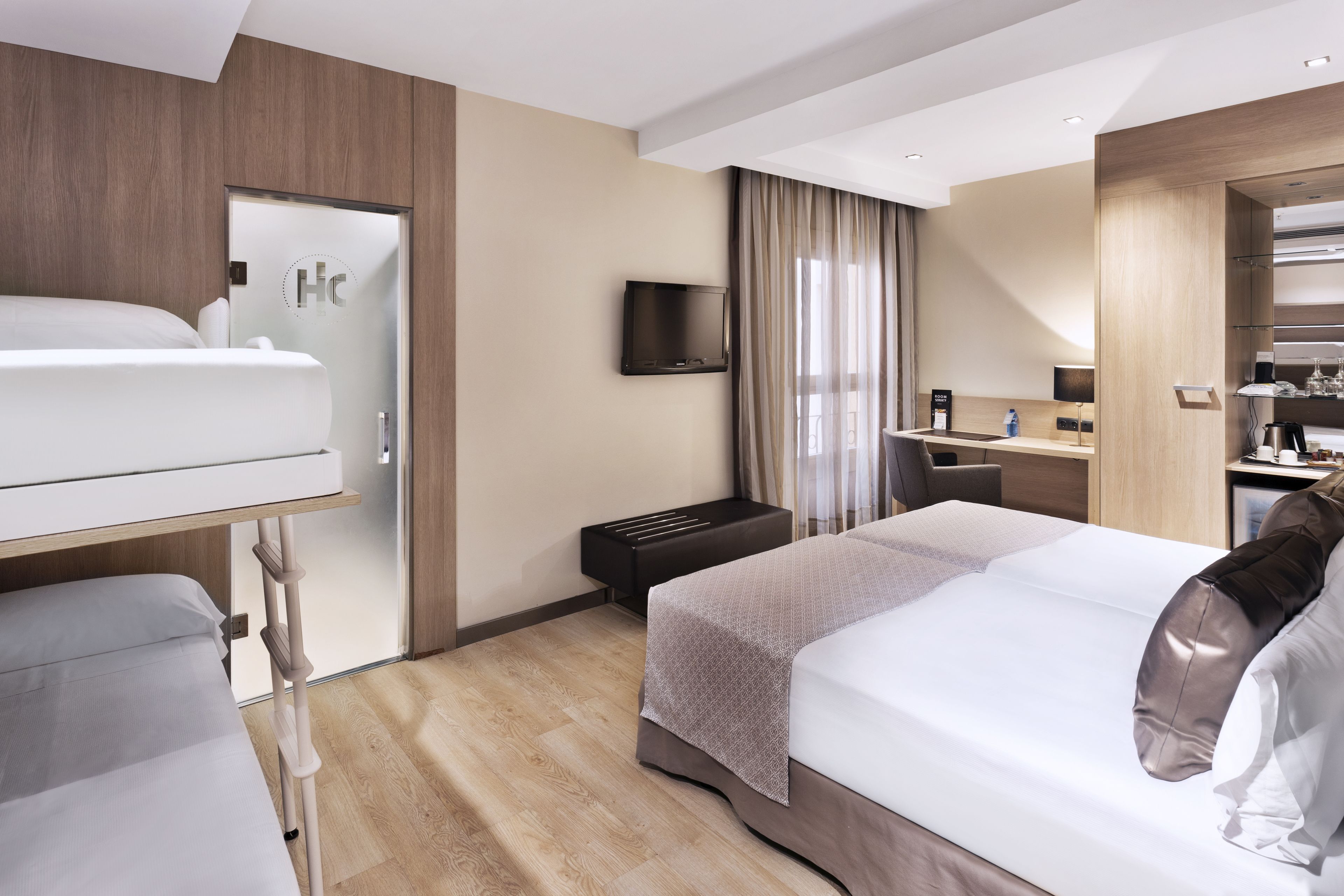 Ein Hotelzimmer mit Bett, Schreibtisch, Fernseher und Kleiderschrank.