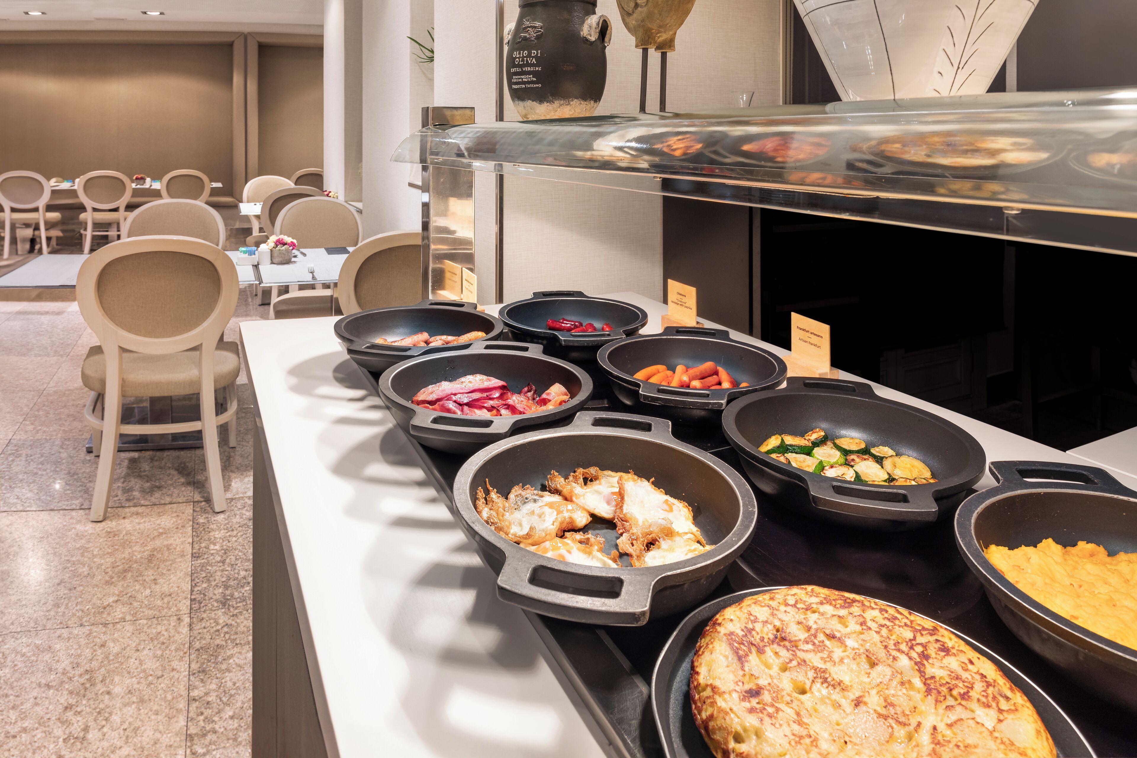 Un bufé con diversos platos, como tortillas y verduras, en un ambiente de hotel.