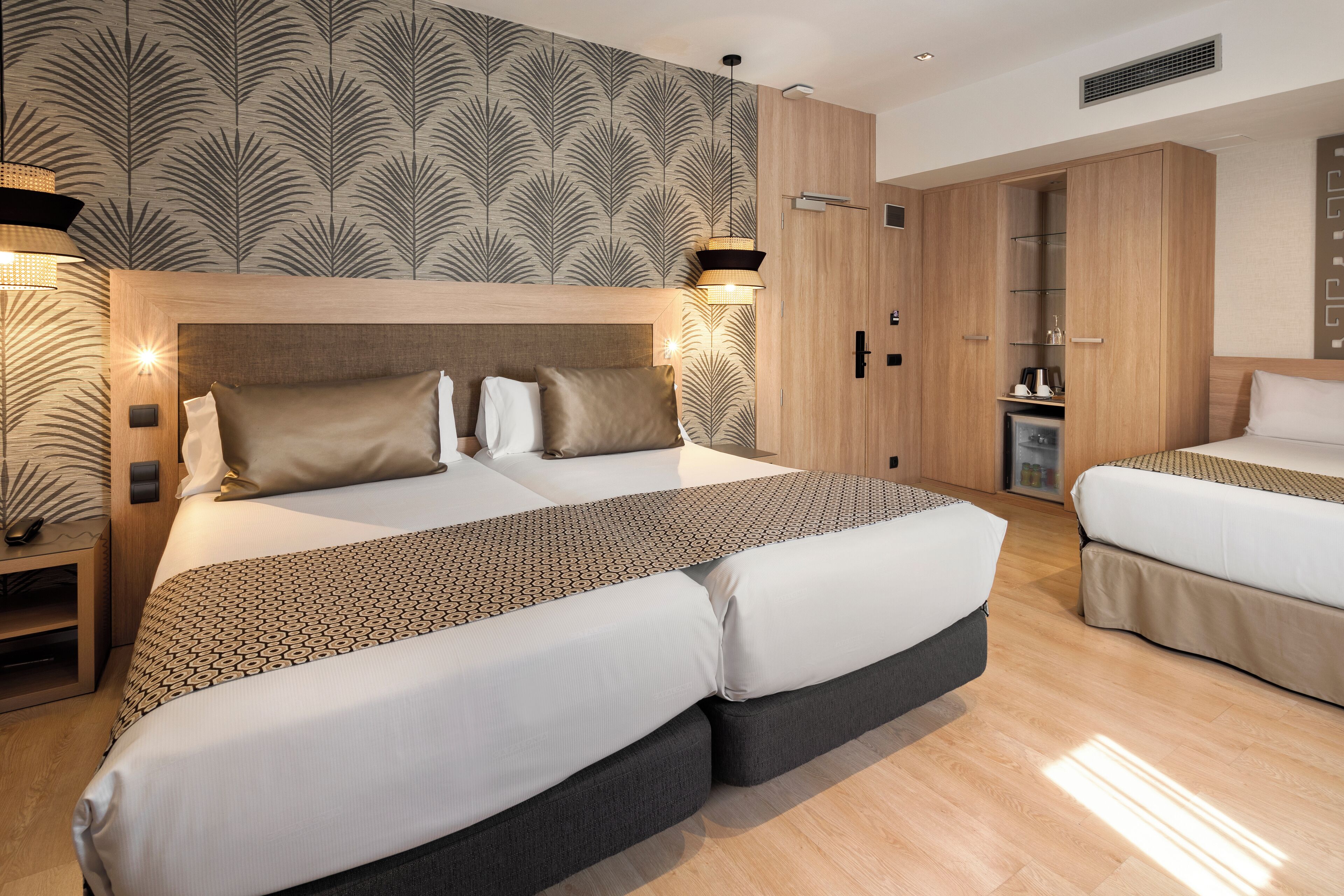 A modern hotel room with a large bed, a smaller bed, and a wardrobe.