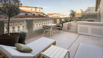 Eine Dachterrasse mit Sitzgelegenheit, einem kleinen Tisch und einem Blumentopf.