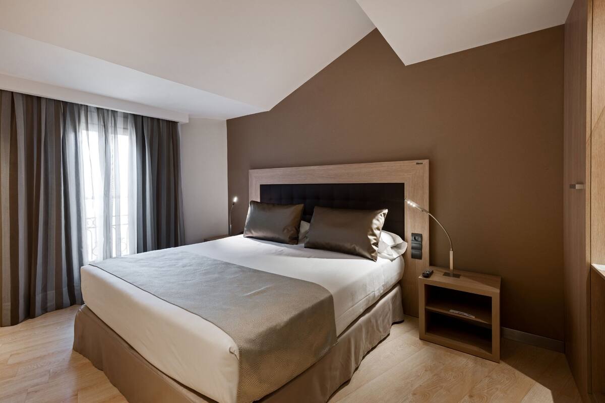 A modern bedroom with a large bed, a nightstand, and a lamp.