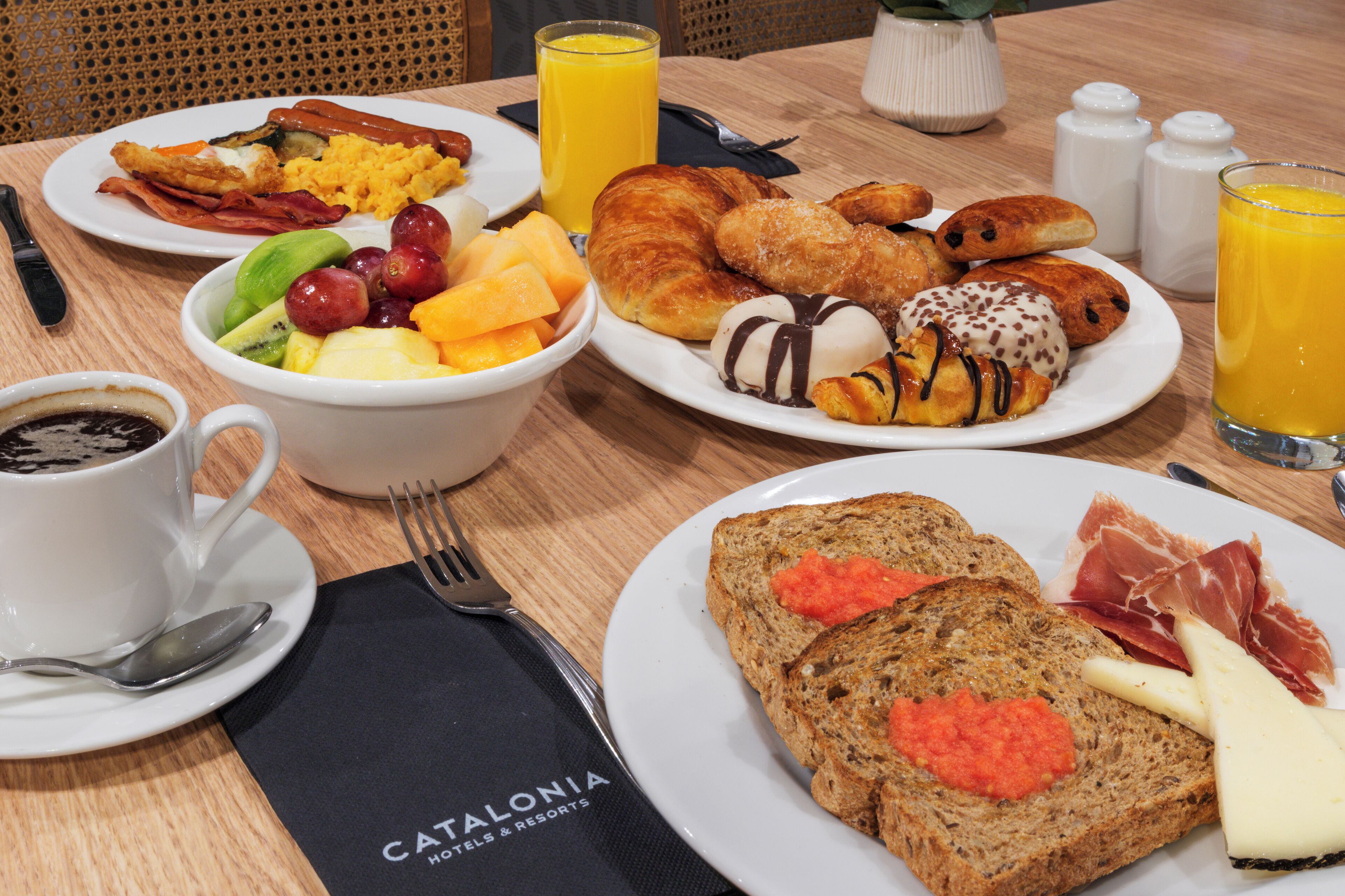 Ein Frühstückstisch mit Speisen, einer Kaffeetasse und einem Glas Orangensaft.