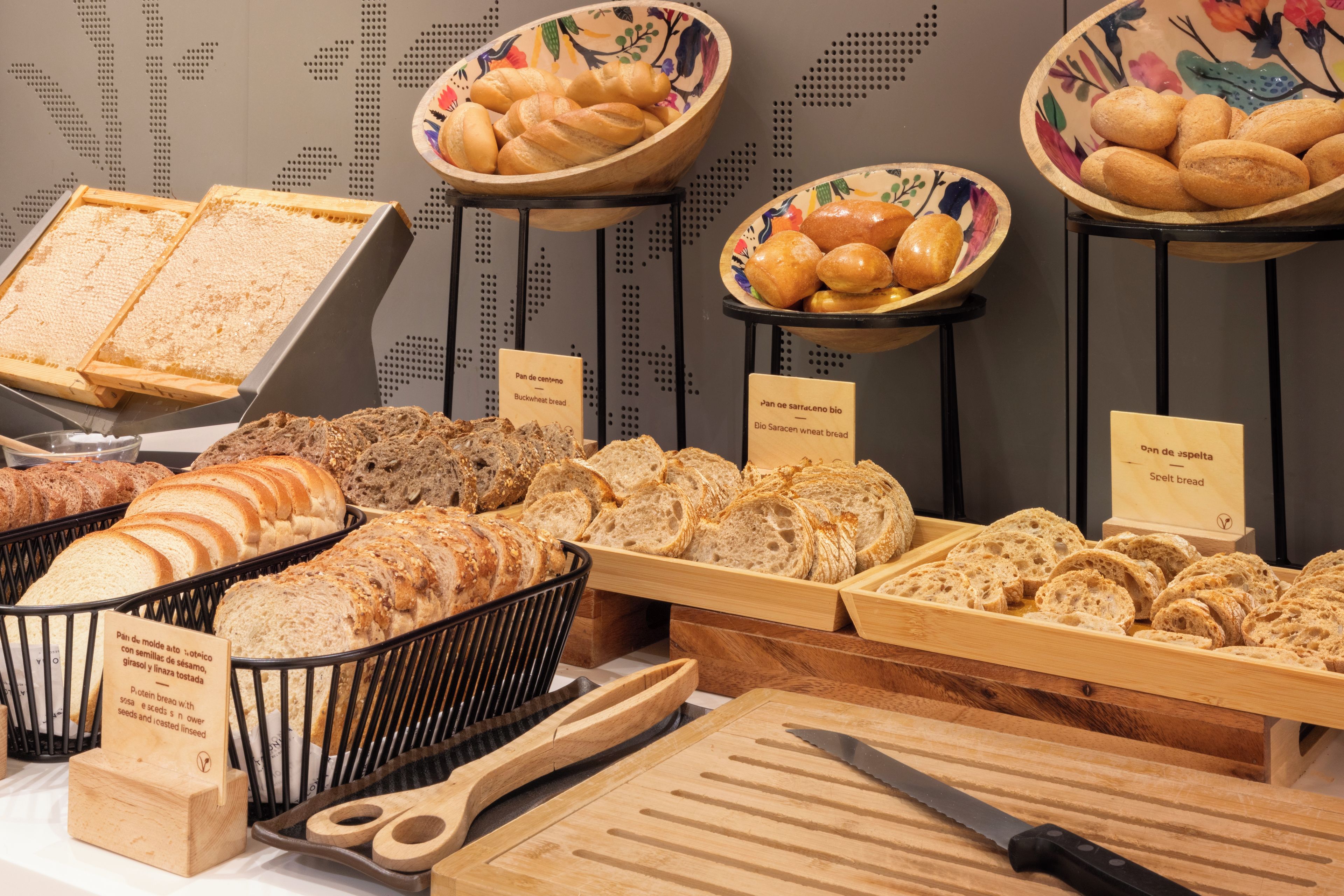 Variedad de panes y pasteles exhibidos en un mostrador con etiquetas.