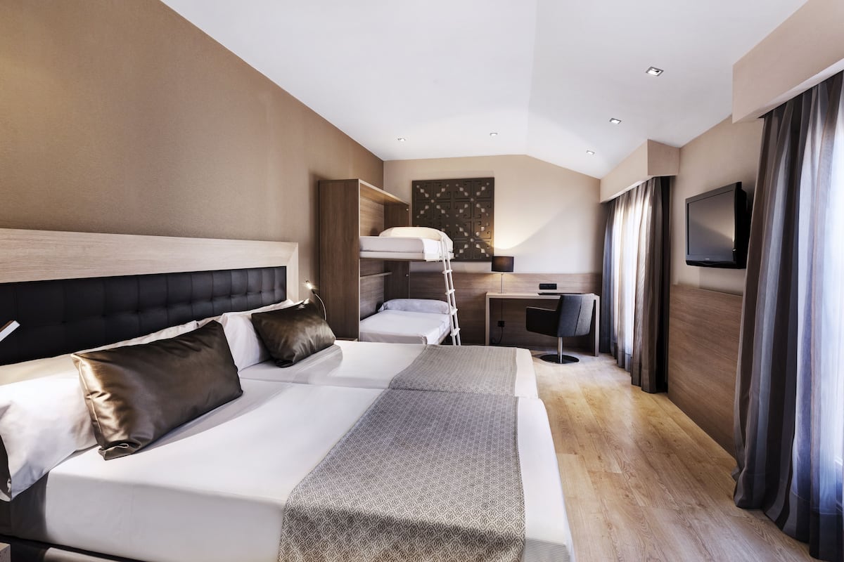 A modern hotel room with a large bed, a desk, and a TV.