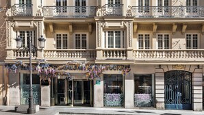 Un edificio histórico con balcones ornamentados, una tienda con un cartel y una entrada con rejas.