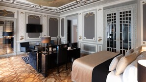 Una lujosa habitación de hotel con una cama grande, un escritorio con computadora, una silla y un televisor.