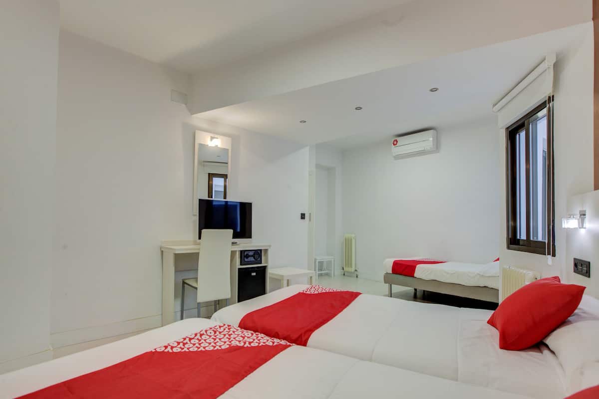 Une chambre d’hôtel avec deux lits, un bureau, une chaise, une télévision et une fenêtre.