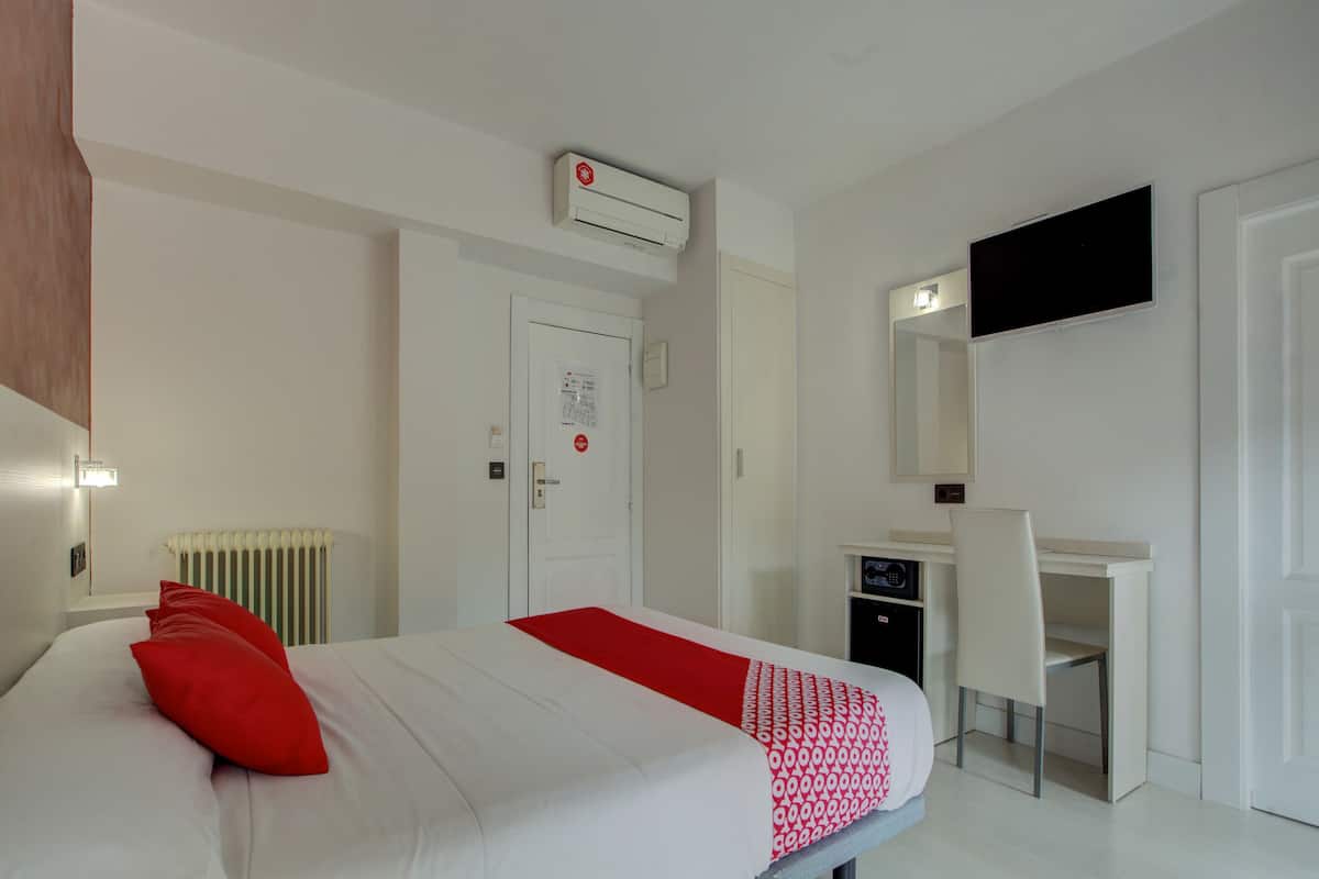 Une chambre d’hôtel équipée d’un lit, d’un bureau, d’une chaise, d’un climatiseur, d’une télévision et d’un radiateur.