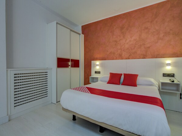 Una habitación de hotel moderna con una cama grande, un armario y una pared de acento roja.