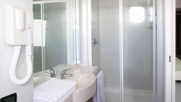 Un bagno con doppio lavandino, uno specchio, cabina doccia e telefono.