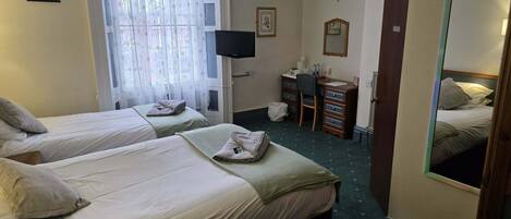 A hotel room with two beds, a desk, a chair, a television, and a mirror.
