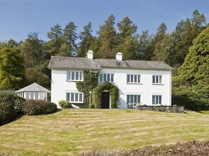 A two-story white house with a symmetrical facade, a central entrance, and a small garden area in front. - High Grassings Country House (Ambleside)