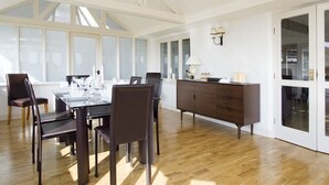 A dining area with a table set for four, wooden chairs, a dark wooden cabinet, and a wall-mounted lamp. - High Grassings Country House (Ambleside)
