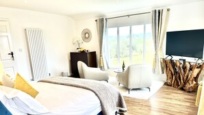 A modern bedroom with a large bed, a TV, and a view of the outdoors. - High Grassings Country House (Ambleside)