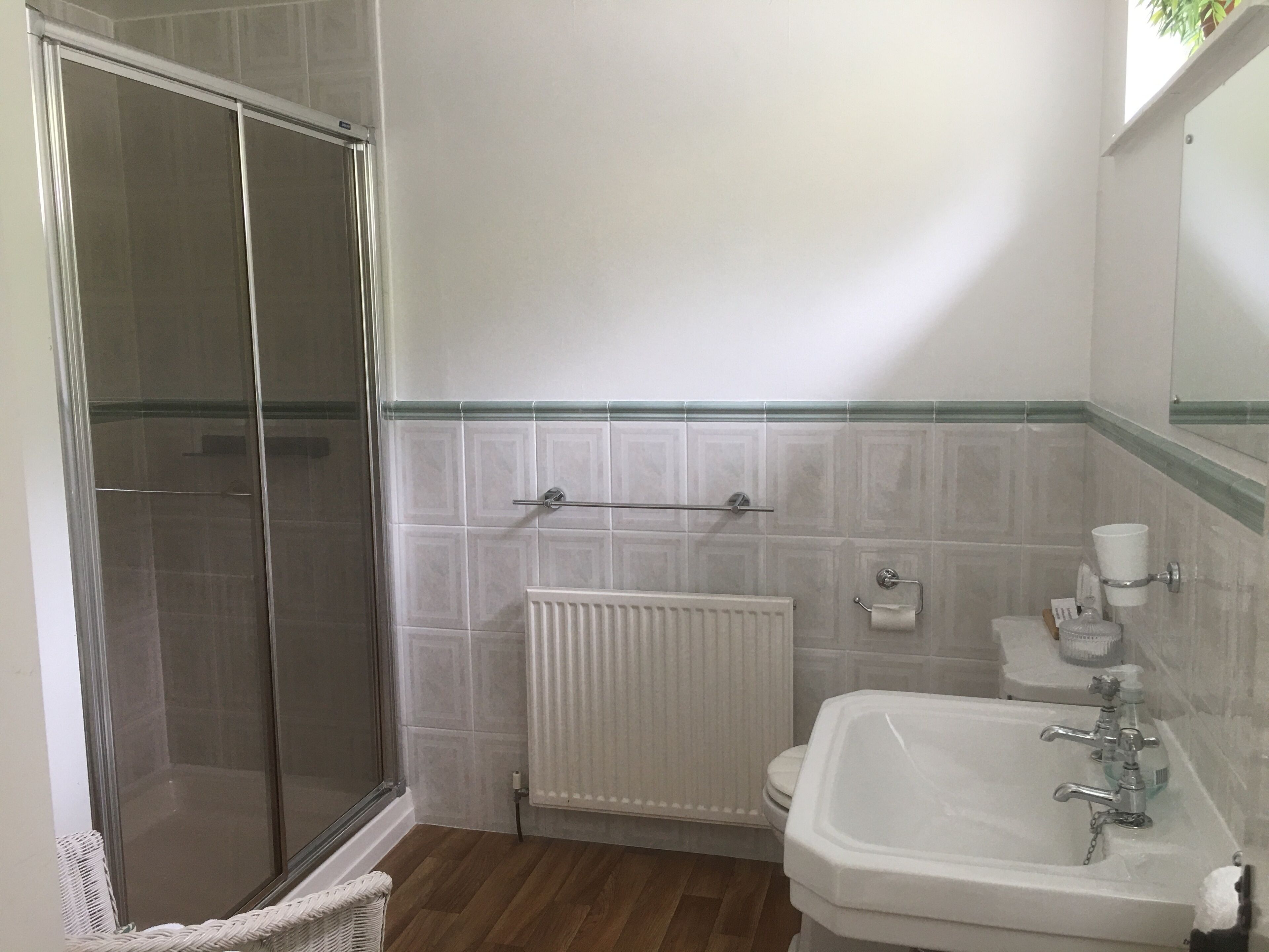 Un baño con cabina de ducha de vidrio, un lavamanos blanco con espejo y un inodoro.