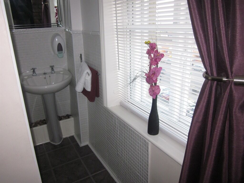 A bathroom with a white sink, a towel rack, and a window with blinds.