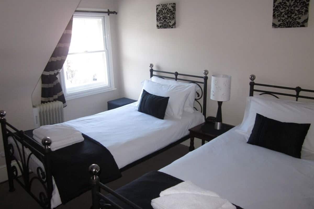 A hotel room with two single beds, a window with a view, and a radiator.