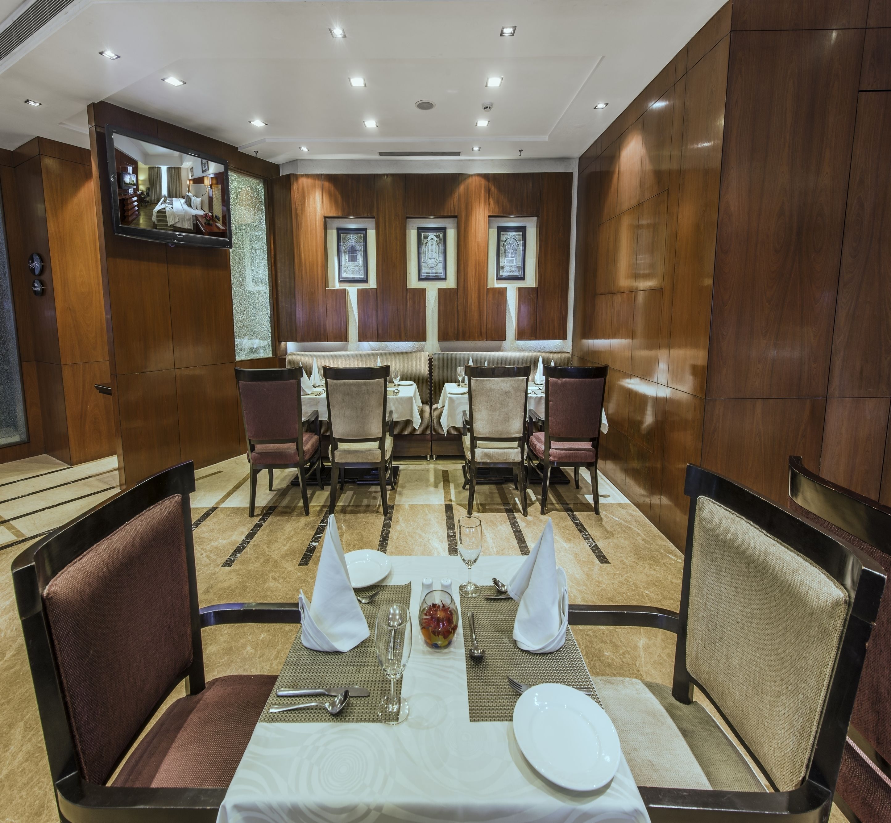 Un comedor de hotel con una larga mesa dispuesta para cuatro personas, rodeada de sillas acolchadas.