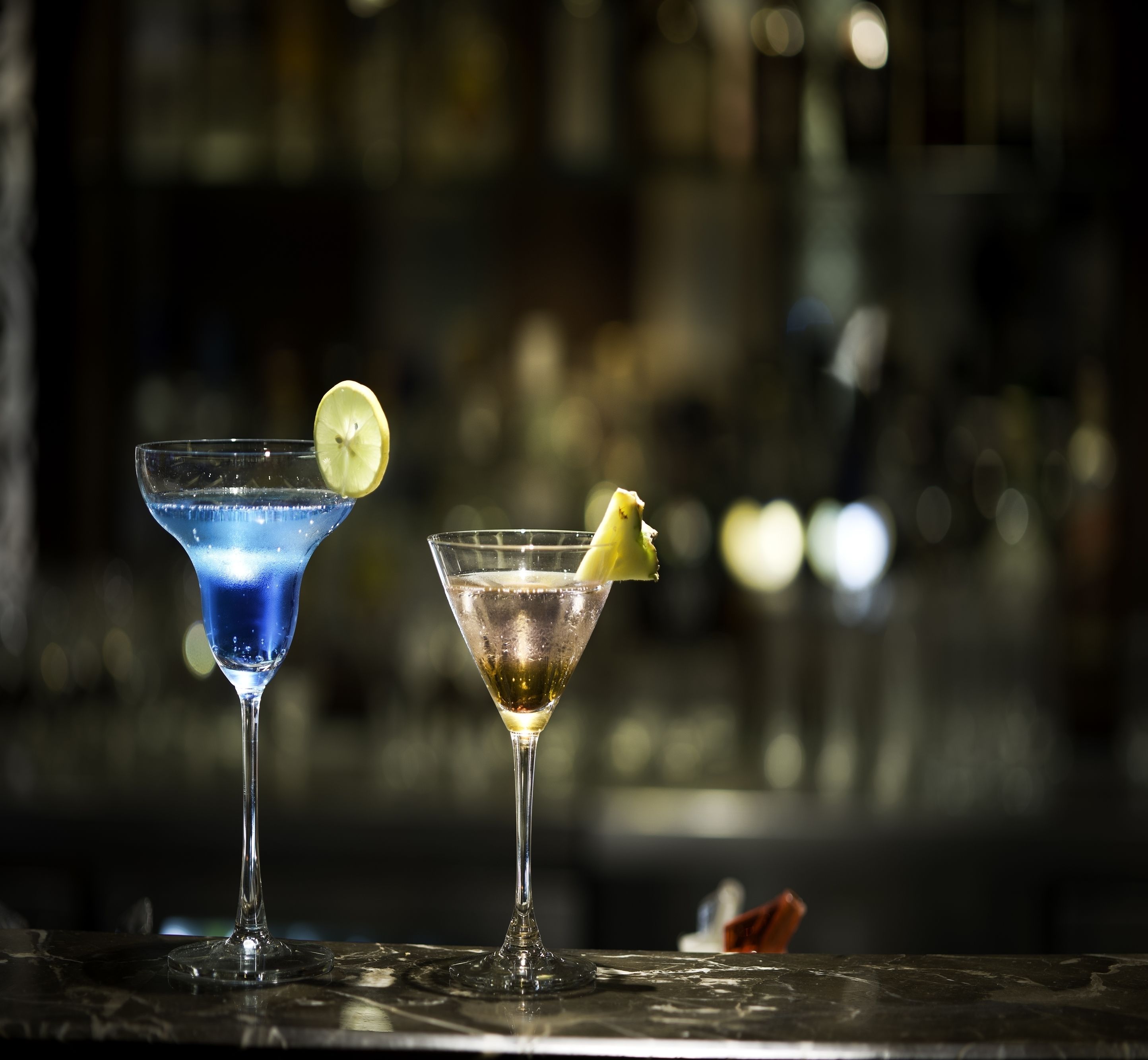 Zwei Cocktails auf einer Bar, unscharfer Hintergrund.