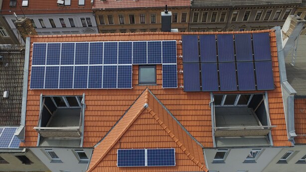 Um edifício alto com várias varandas, janelas amplas e painéis solares no telhado.