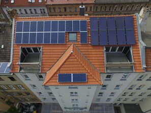 Un edificio de gran altura con varios balcones, ventanas amplias y paneles solares en el techo.