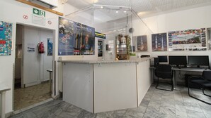 Uma área de recepção com balcão, assentos e cartazes informativos nas paredes.