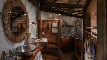 Relax in a cozy bathroom with a large mirror, metal basin, and wooden cabinets.