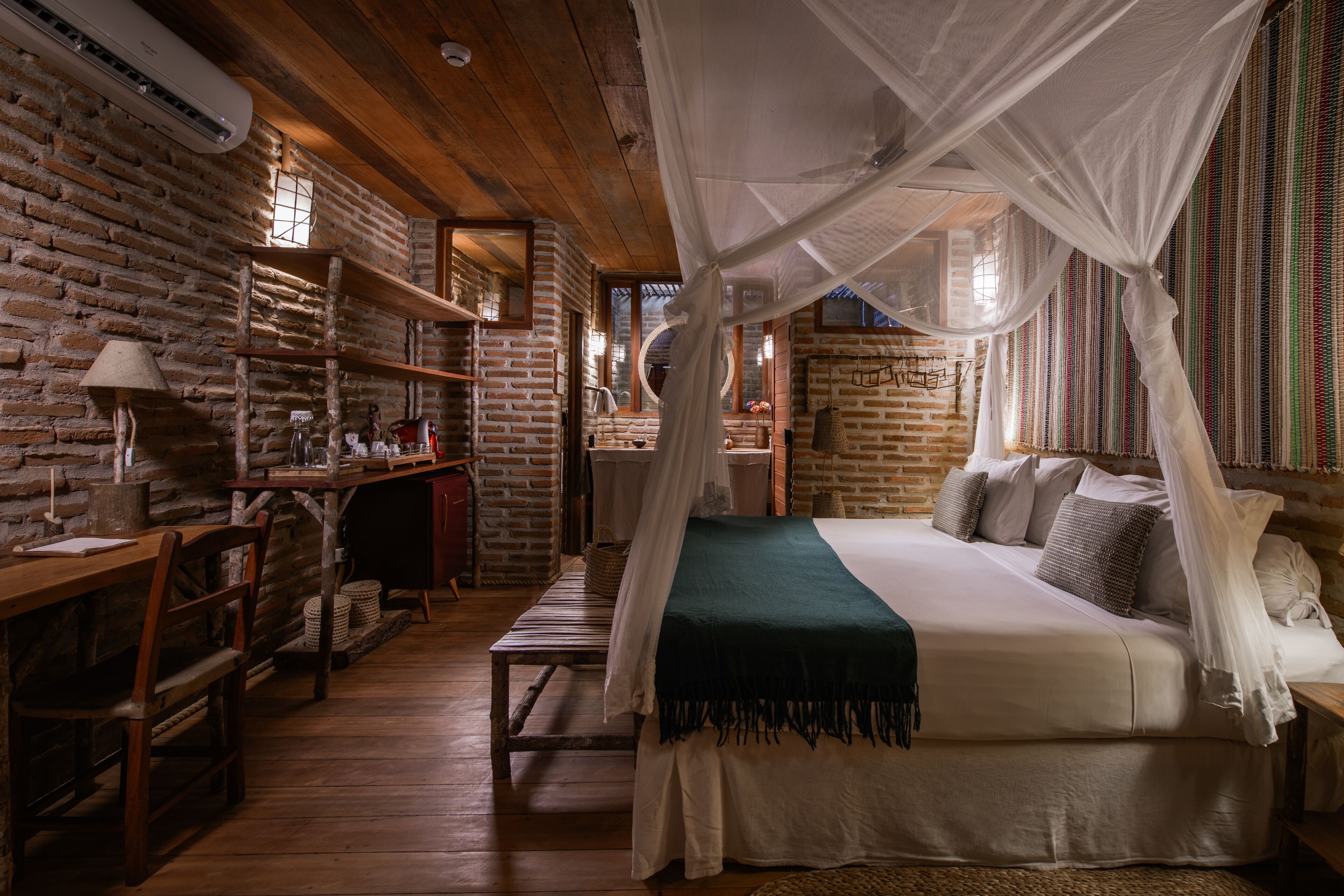 Una habitación rústica con cama bajo dosel, muebles de madera y pared de ladrillo.