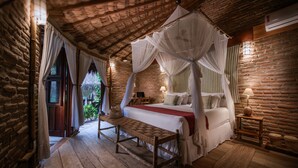 Une chambre à coucher au style rustique, avec un lit à baldaquin, un plancher en bois et un mur en briques.