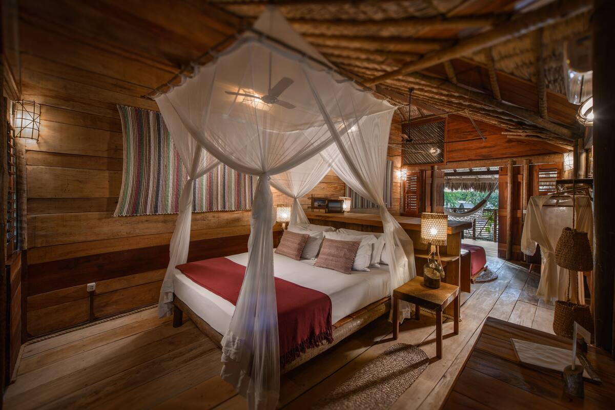 A wooden room with a bed, a nightstand, and a hanging chair.