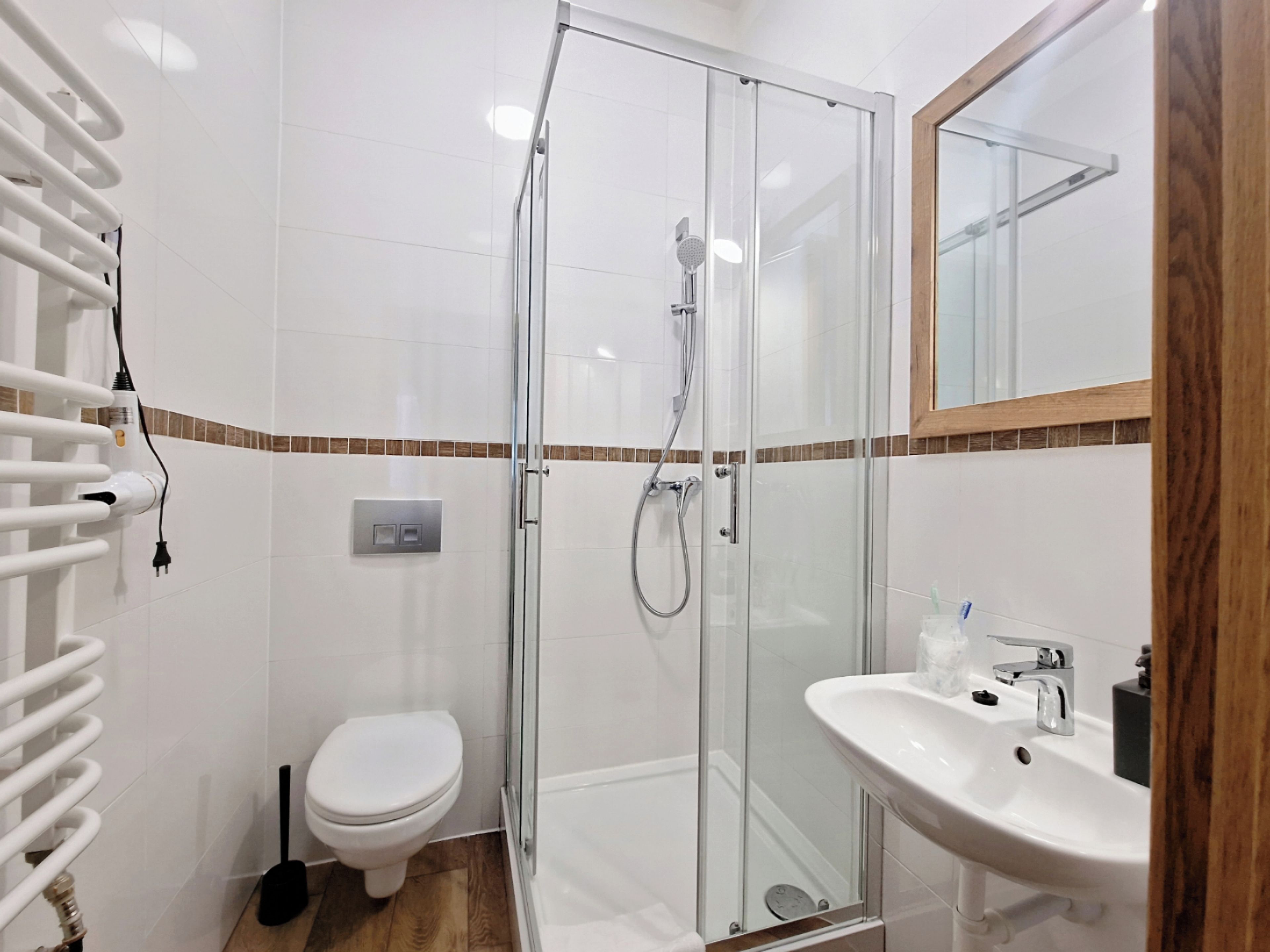 Une salle de bain moderne avec une douche à parois de verre, des toilettes blanches et un lavabo avec un miroir au-dessus.