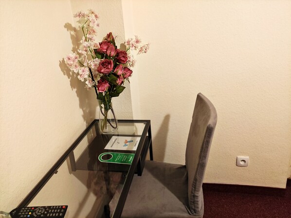 Una pequeña mesa con un florero, un control remoto y un cartel que indica los servicios de la habitación.