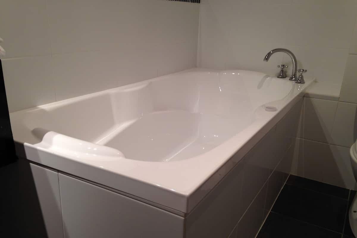 Un baño moderno con una bañera blanca, zona de ducha separada y un inodoro.