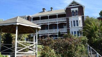 A large, two-story building with a prominent balcony and a covered pavilion in the foreground.