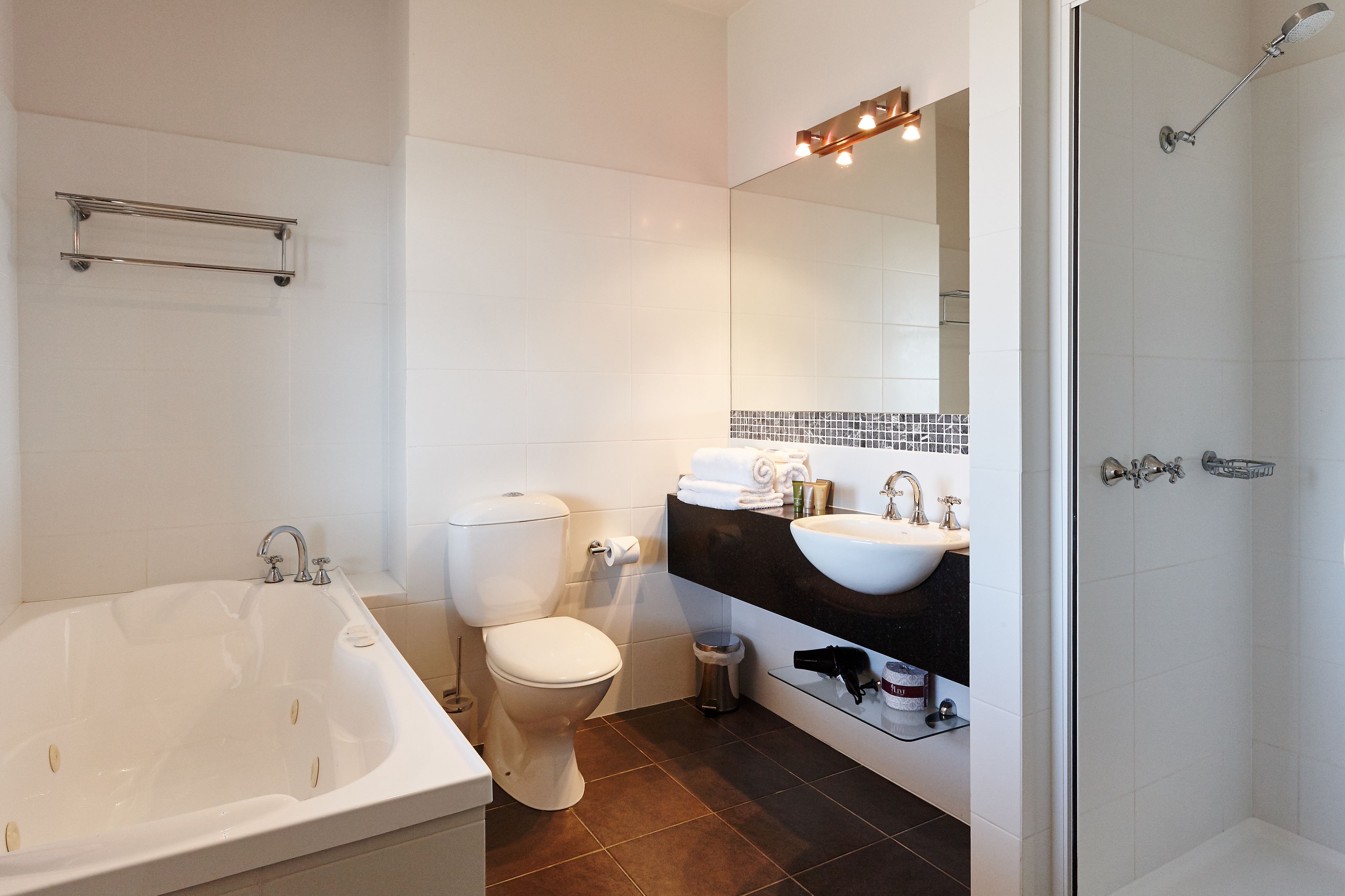 A modern bathroom with a bathtub, toilet, sink, and shower.
