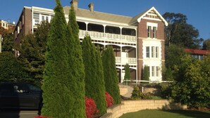 A large, two-story house with a balcony, surrounded by well-maintained lawns and trees. - Auldington Hotel (Launceston)