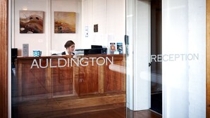 A reception area with a wooden reception desk, framed artwork on the wall, and a sign indicating 'RECEPTION'. - Auldington Hotel (Launceston)