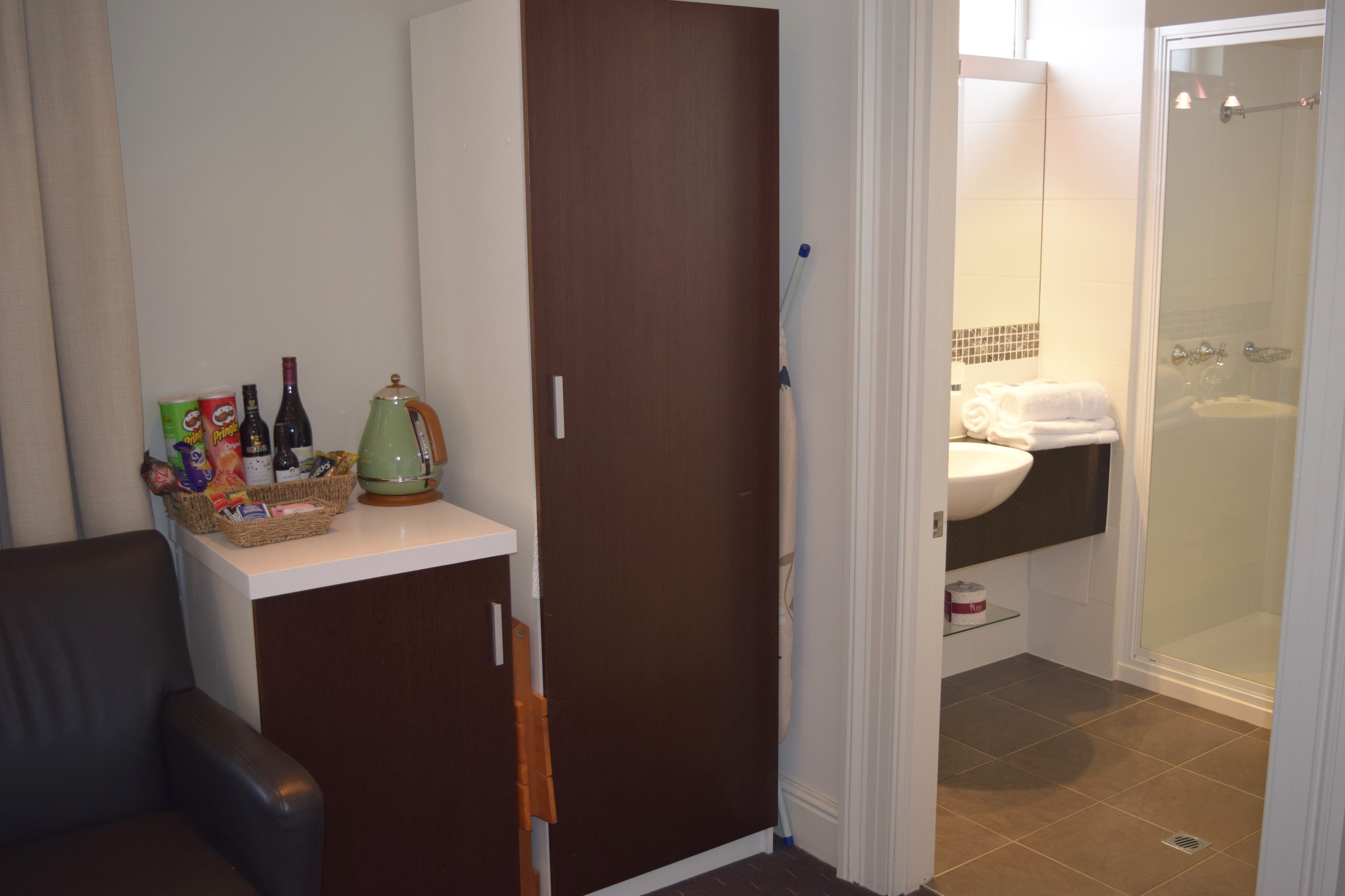 A compact bathroom with a shower, a sink, and a small shelf.
