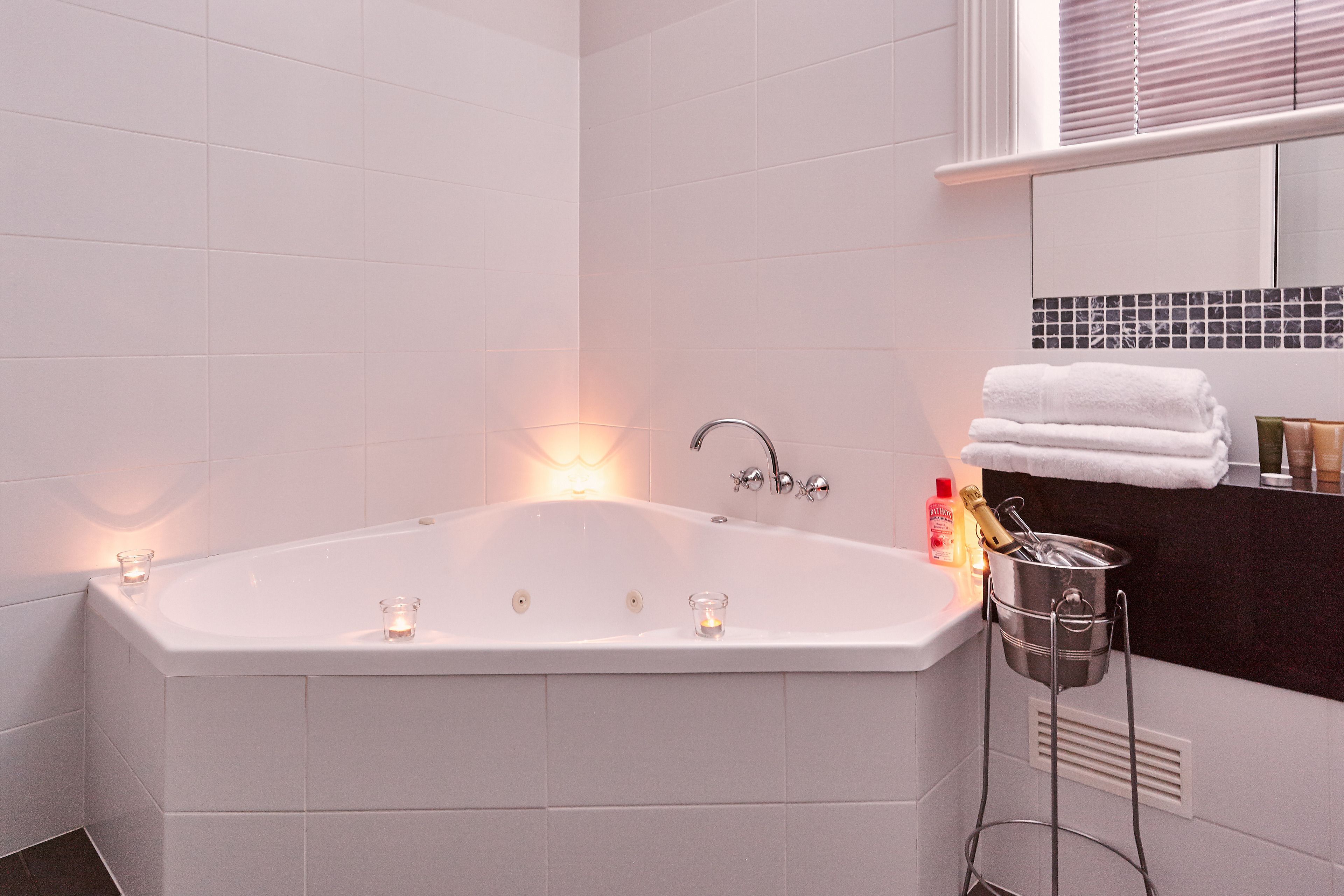Une salle de bain moderne avec une grande baignoire, un miroir et un porte-serviettes.