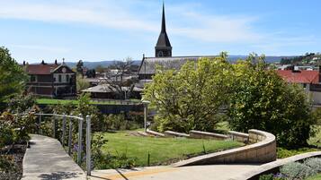A park with a curved pathway, a church with a tall steeple, and residential buildings in the background.