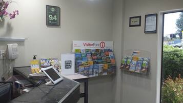 Un mostrador de recepción con una computadora, un teléfono y una pared que muestra varios folletos de viajes.