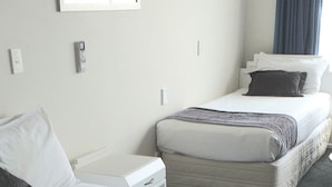 Habitación de hotel con dos camas, una mesita de noche, un espejo y una ventana con cortinas.