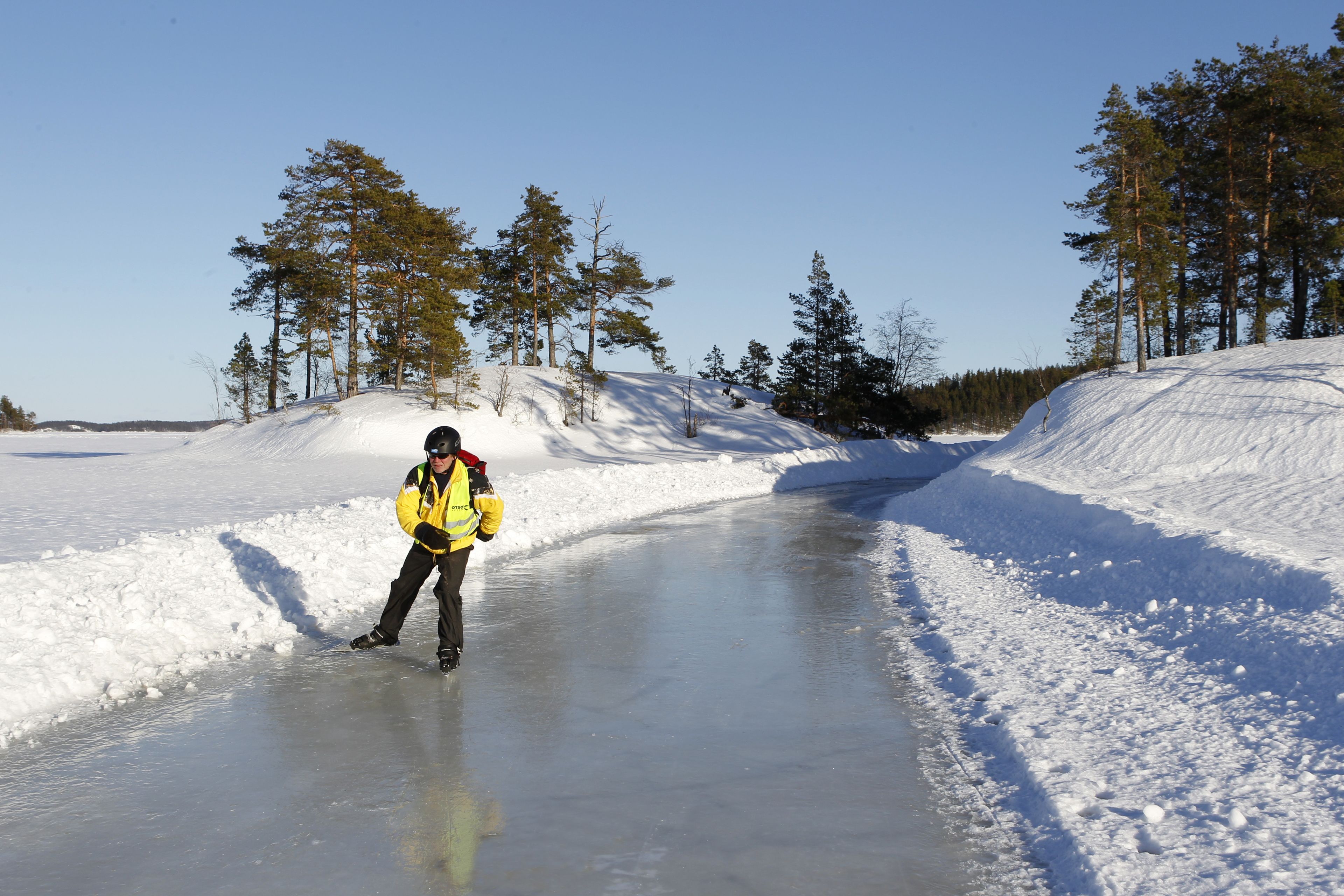 A person ice skating on a frozen lake surrounded by trees.