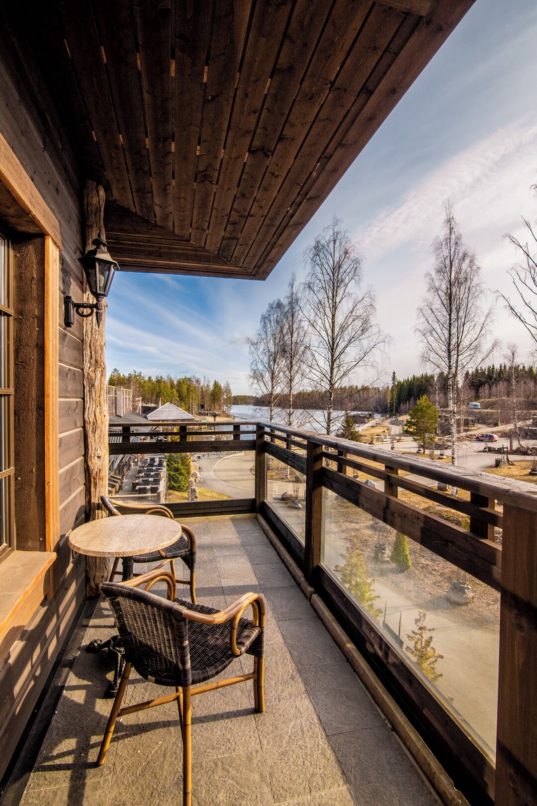 A wooden balcony with a view of a snowy landscape and a road.