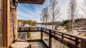 A wooden balcony with a view of a snowy landscape and a road.