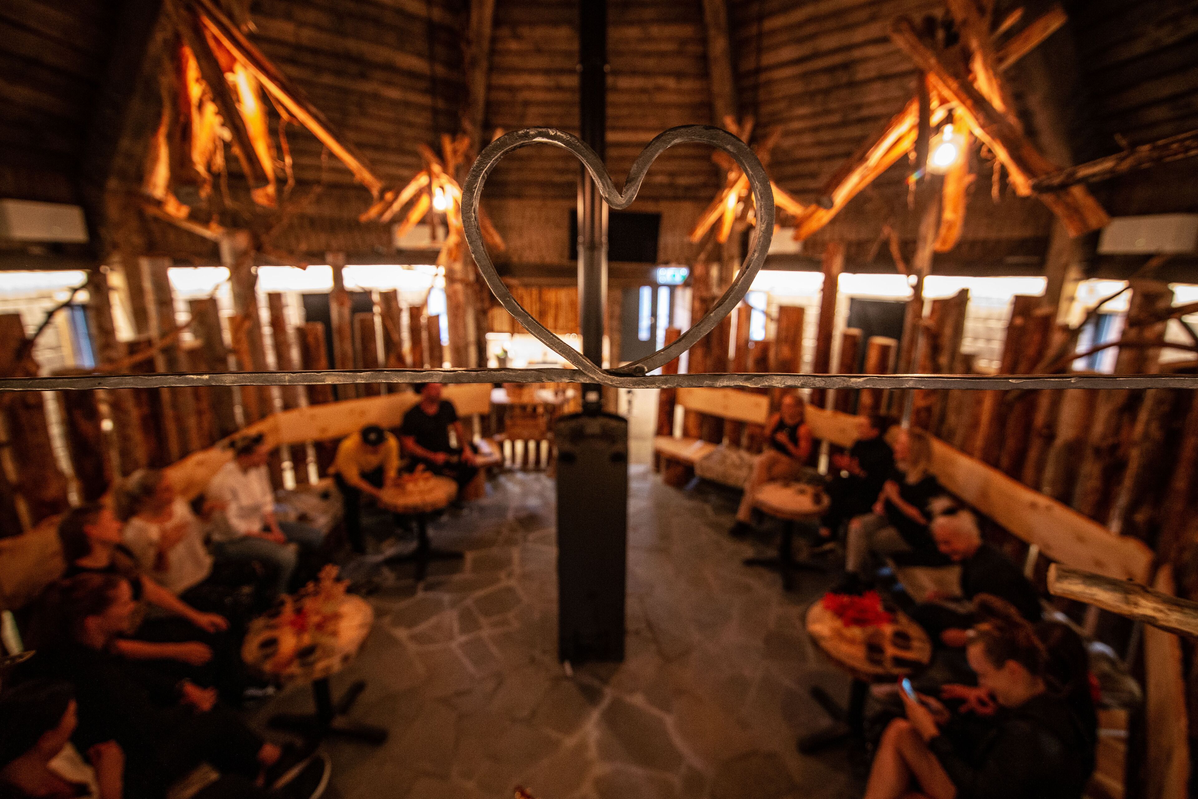 Un interior rústico con un adorno metálico en forma de corazón, muebles de madera y suelo de piedra.
