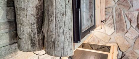 A rustic kitchen with a wooden countertop, a stainless steel sink, and a stone wall.